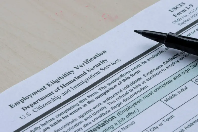 Employment Eligibility Verification form with black pen resting on document
