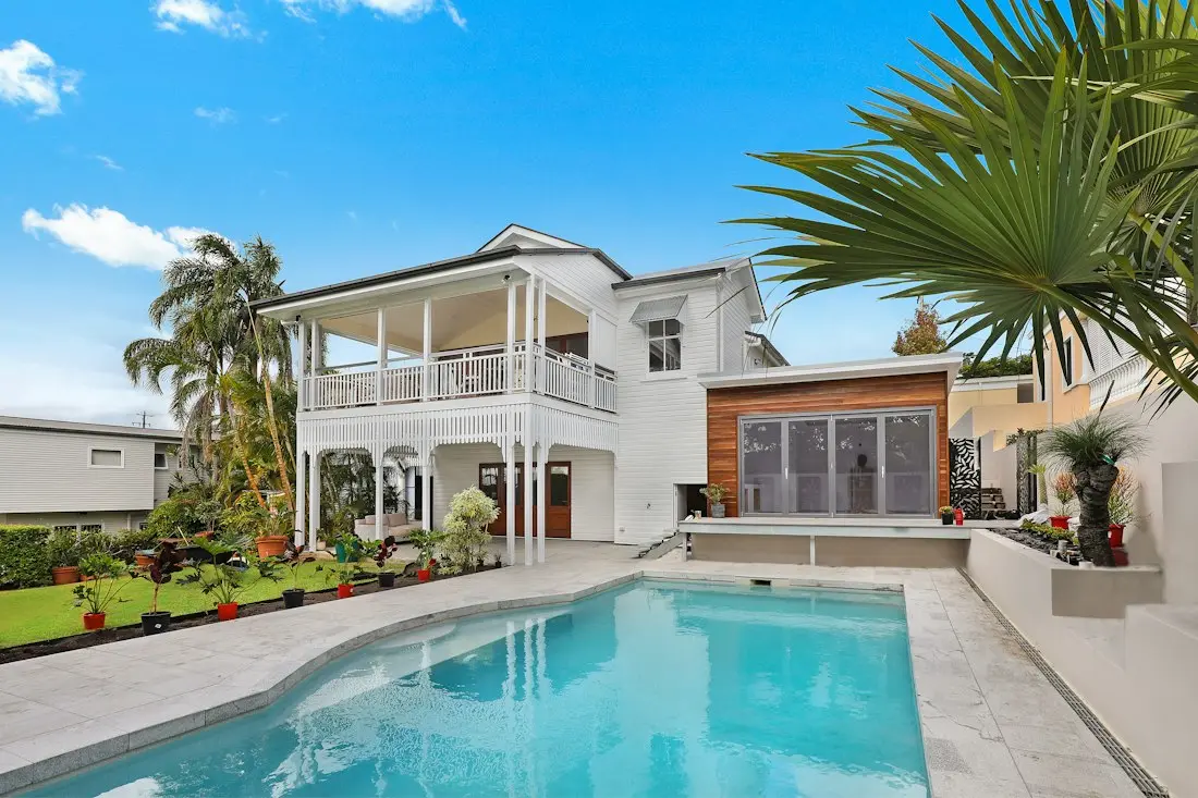 Modern two-story white house with pool, wooden feature wall, and palm trees